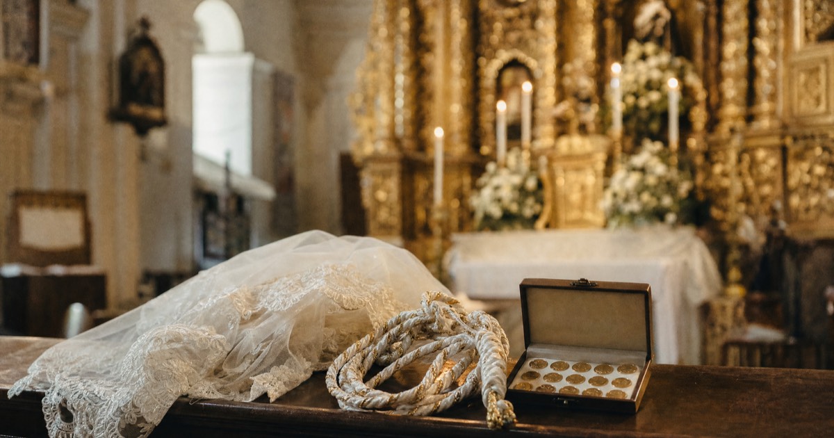 Cord sponsors placing a decorative yugal over a wedding couple during a Filipino Catholic church ceremony